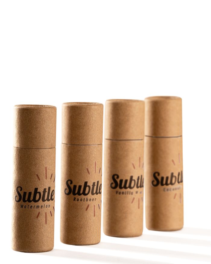 Four Subtle lip balm tubes in a row, casting long afternoon shadows